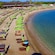 An oceanfront beach club with lounge chairs, umbrellas and a large tent